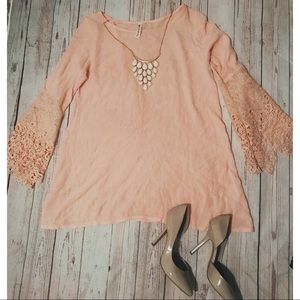 Peach colored blouse with flared lace sleeves